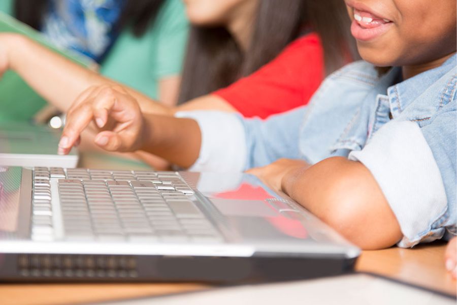 closeup of a boy typing on a laptop